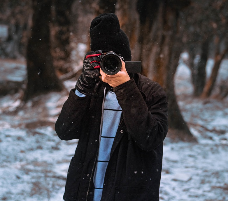 Male photographer capturing winter in the forest